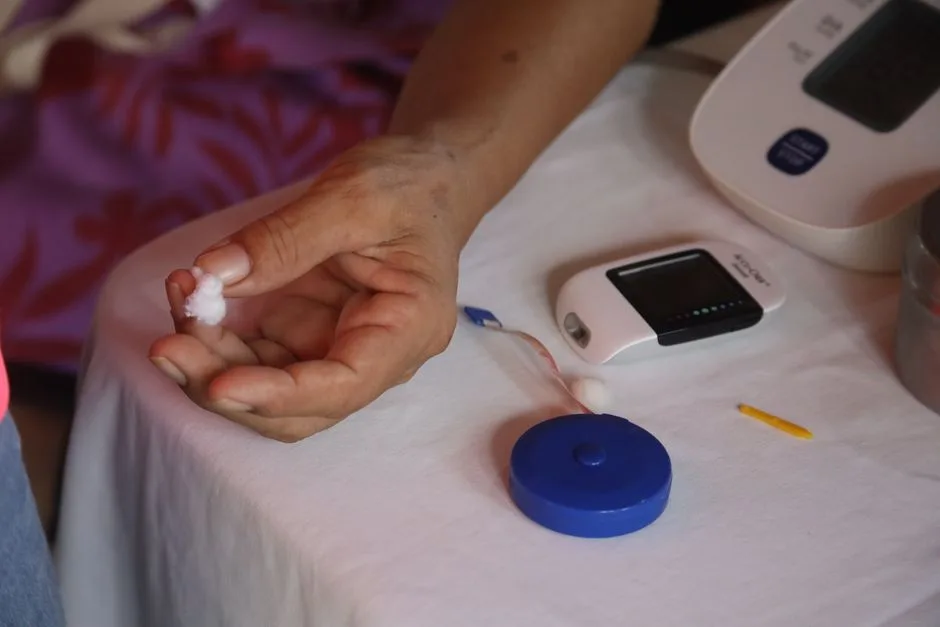 Elderly hand beside a glucometer and blood pressure cuff