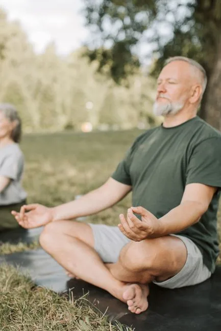 Elderly man doing seated yoga outdoors