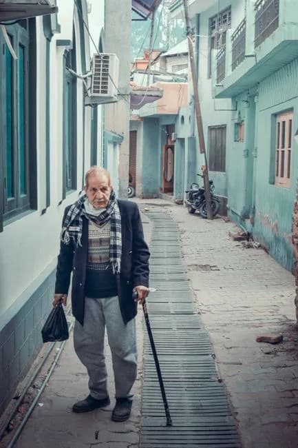 Elderly Indian man walking with a cane near home