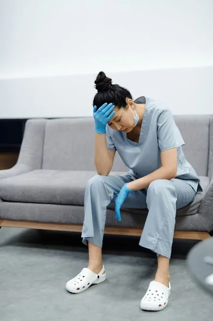 Exhausted caregiver sitting with head in hand
