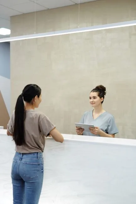 Hospital reception desk with staff assisting a visitor