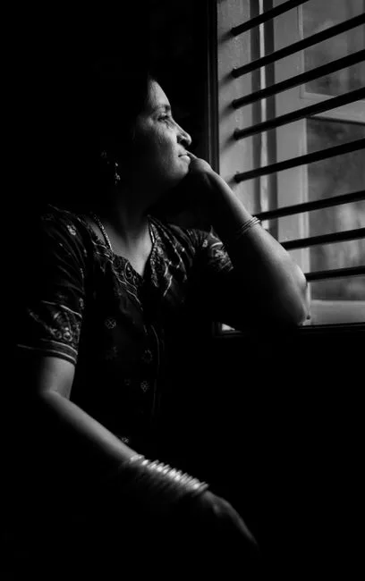 Indian woman in a sari sitting pensively by a window