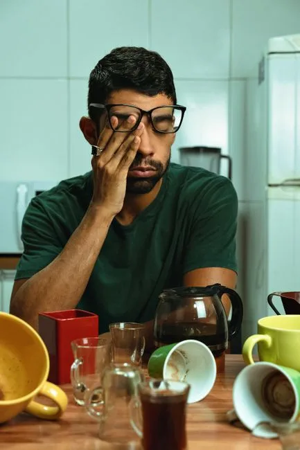 Exhausted caregiver at a cluttered kitchen table