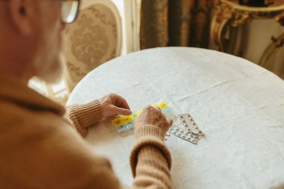 Elderly man sorting pills into a weekly organizer