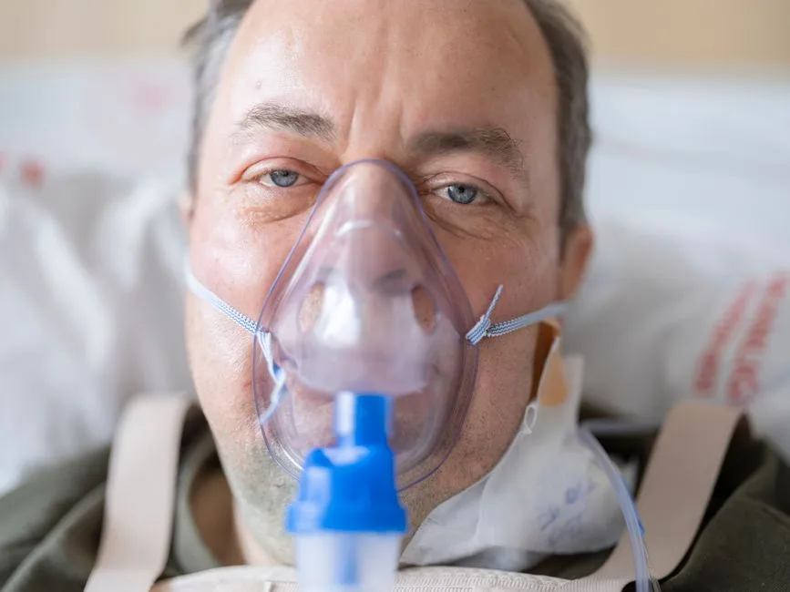 Elderly patient recovering in a hospital bed with oxygen support